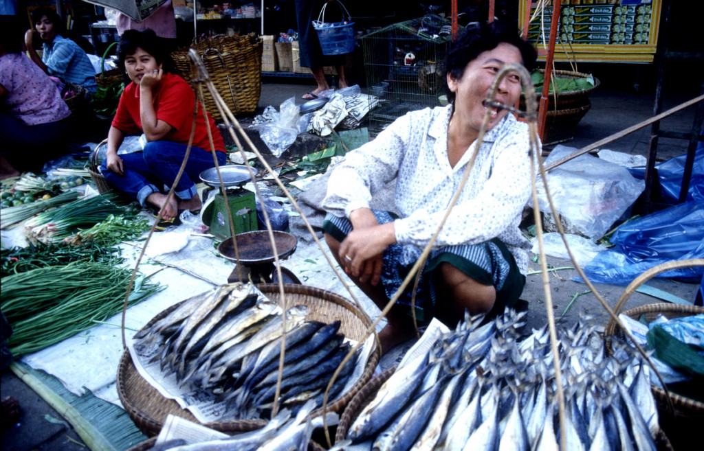 A woman sells fish at a market in Thailand