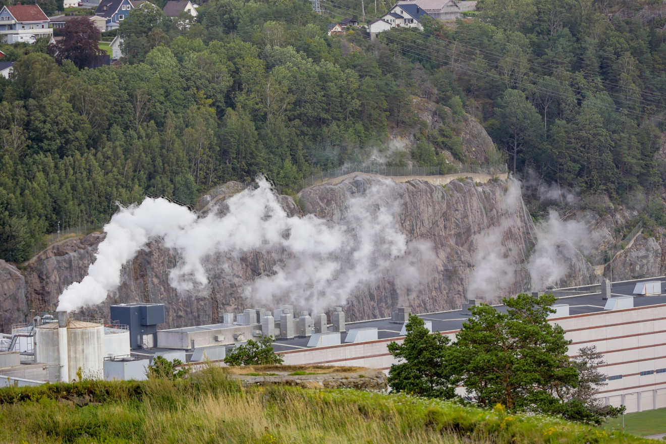 Smoke spreads from a factory to surrounding landscape.