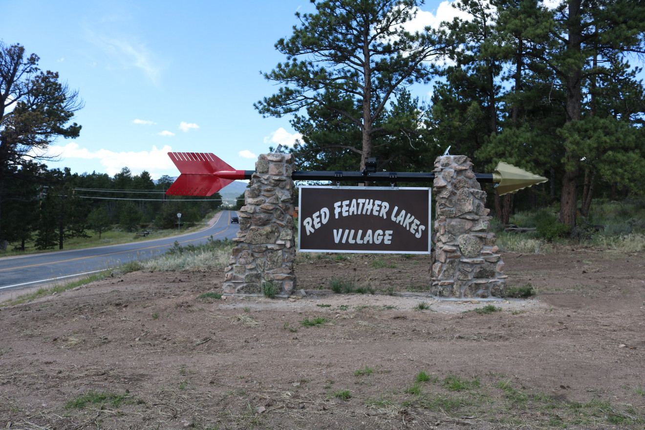 Sign on the edge of a wooded road reads "Red Feather Lakes Village."