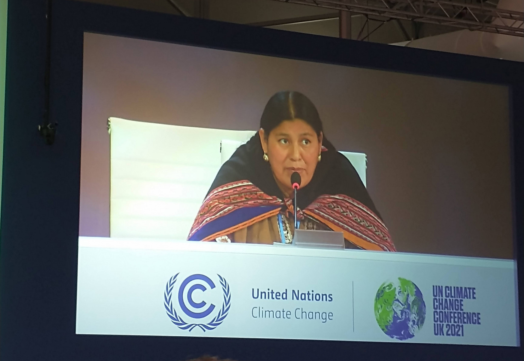 Angelica Ponce Chambi, shown on a screen, speaks on stage at COP26
