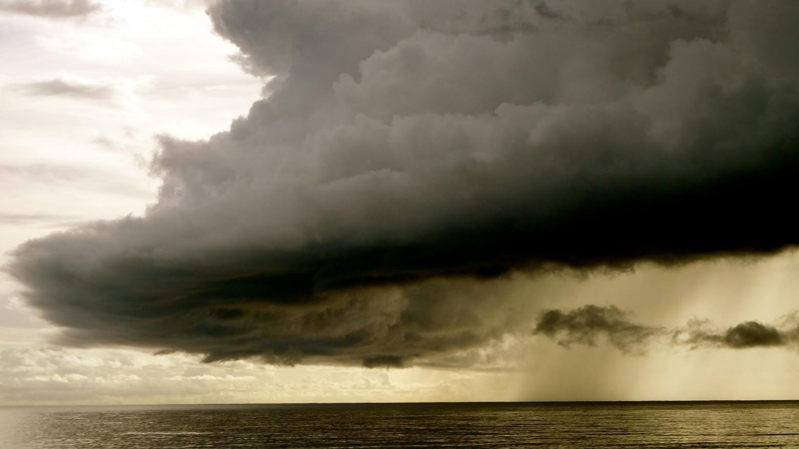 A low, gray storm cloud over a body of water.