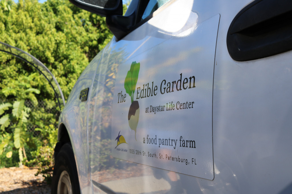 A white pick up truck is parked at the farm, with a decal on the side describing Daystar as, "a food pantry farm."