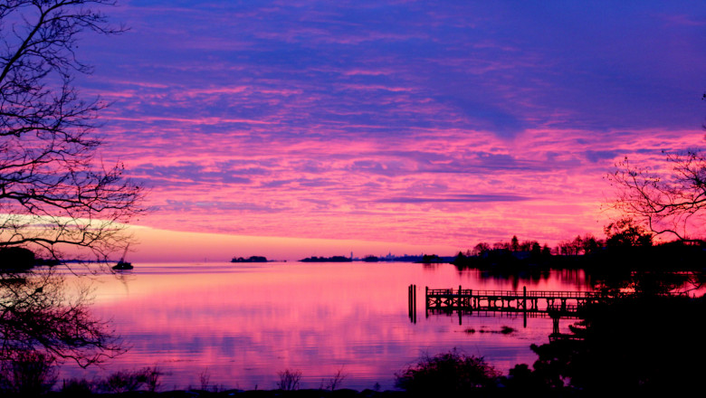 A vibrant pink and purple sunset envelops the Long Island Sound. 