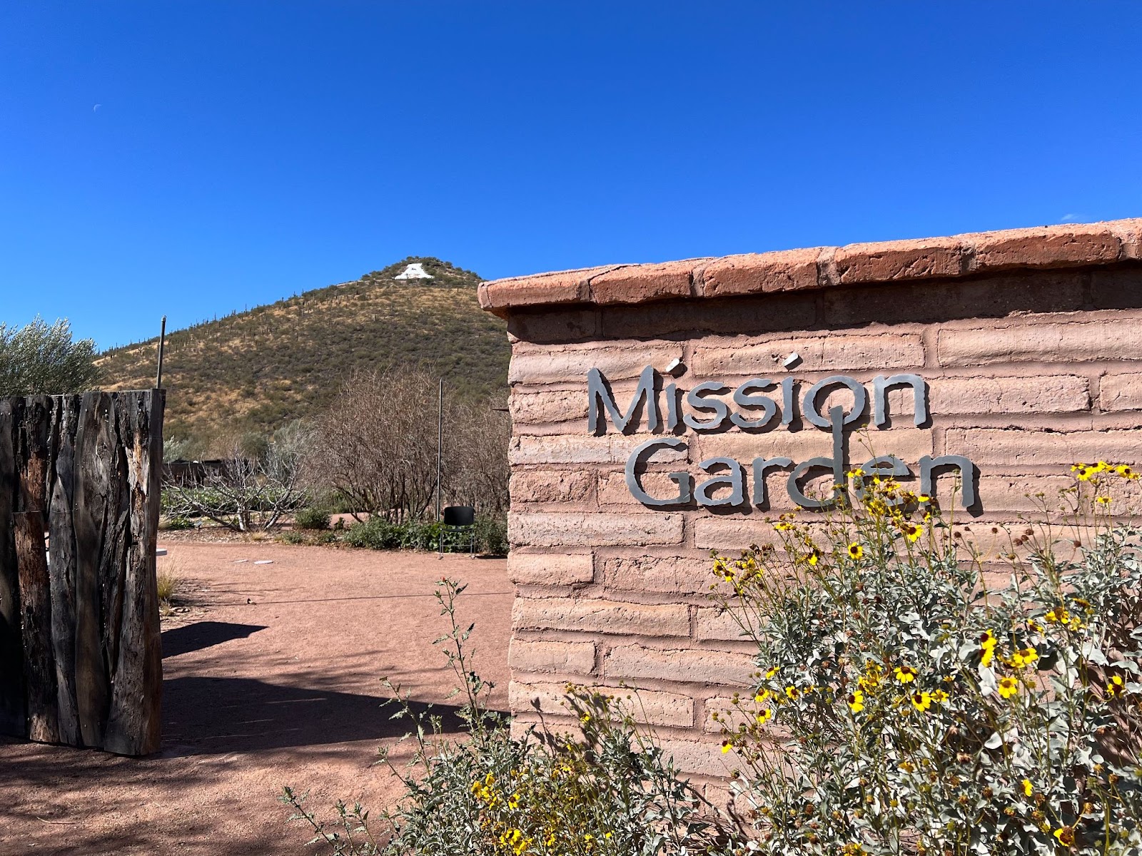 Text on a brick sign reads "Mission Garden"