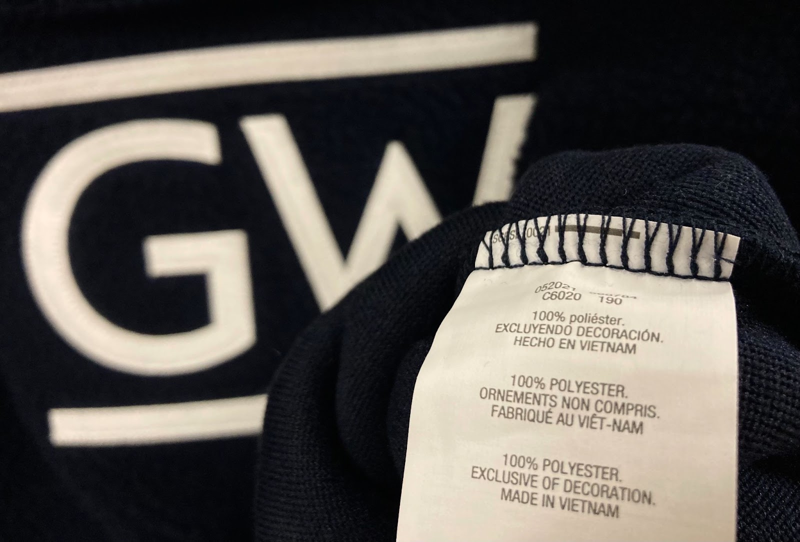 Close up of a tag on a navy blue GW garment which reads "100% Polyester"