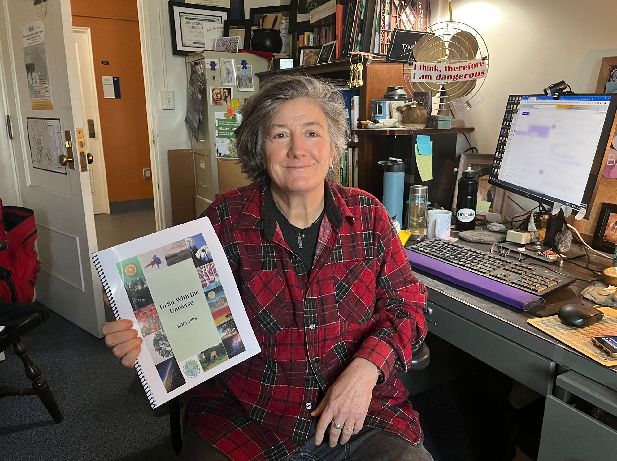 Sociology professor Phoebe Godfrey with the book created by her students.