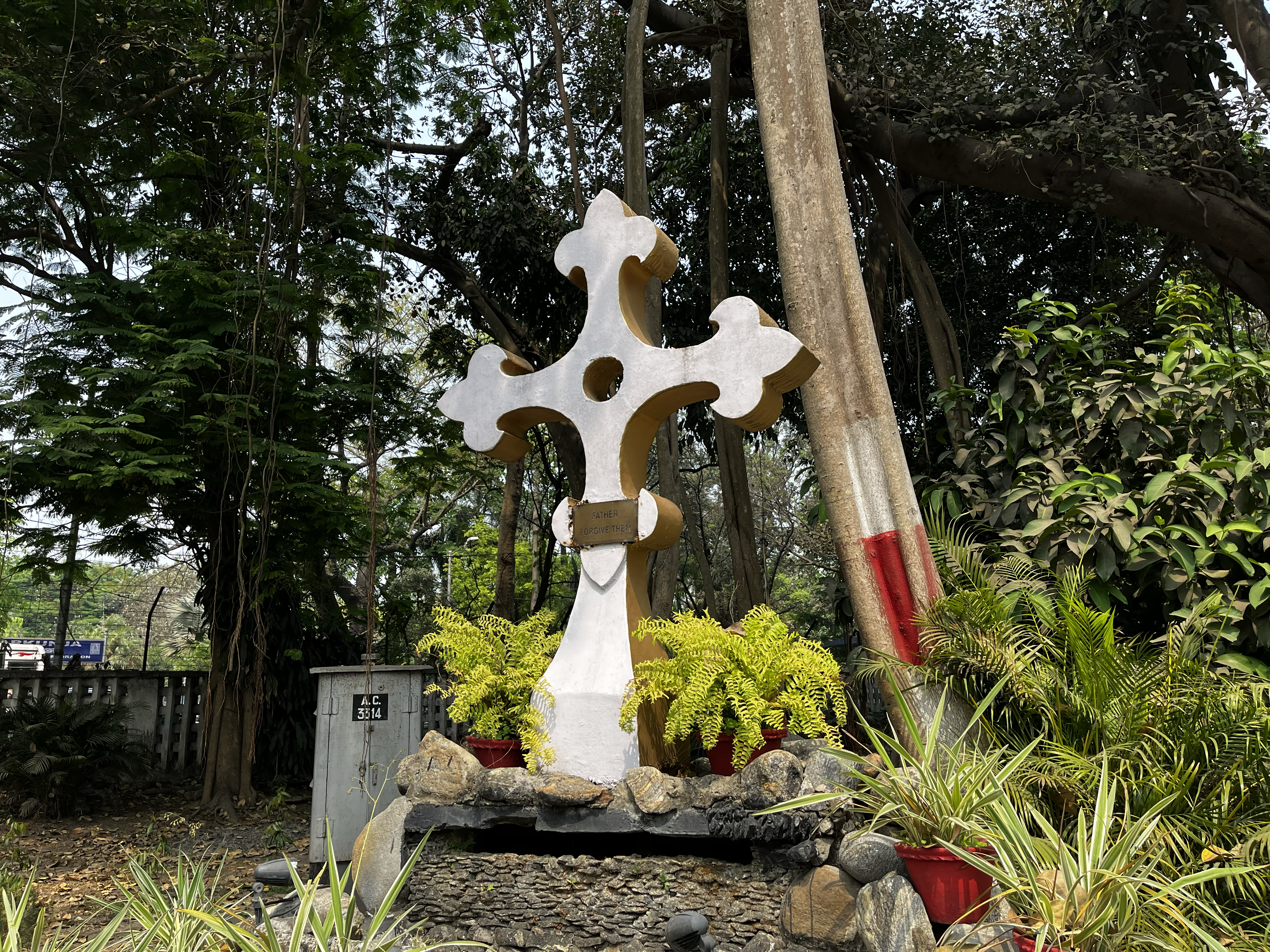 A cross at St. Paul's Cathedral in Kolkata, India surrounded by a lush garden with numerous trees and small ponds on March 8, 2023. 