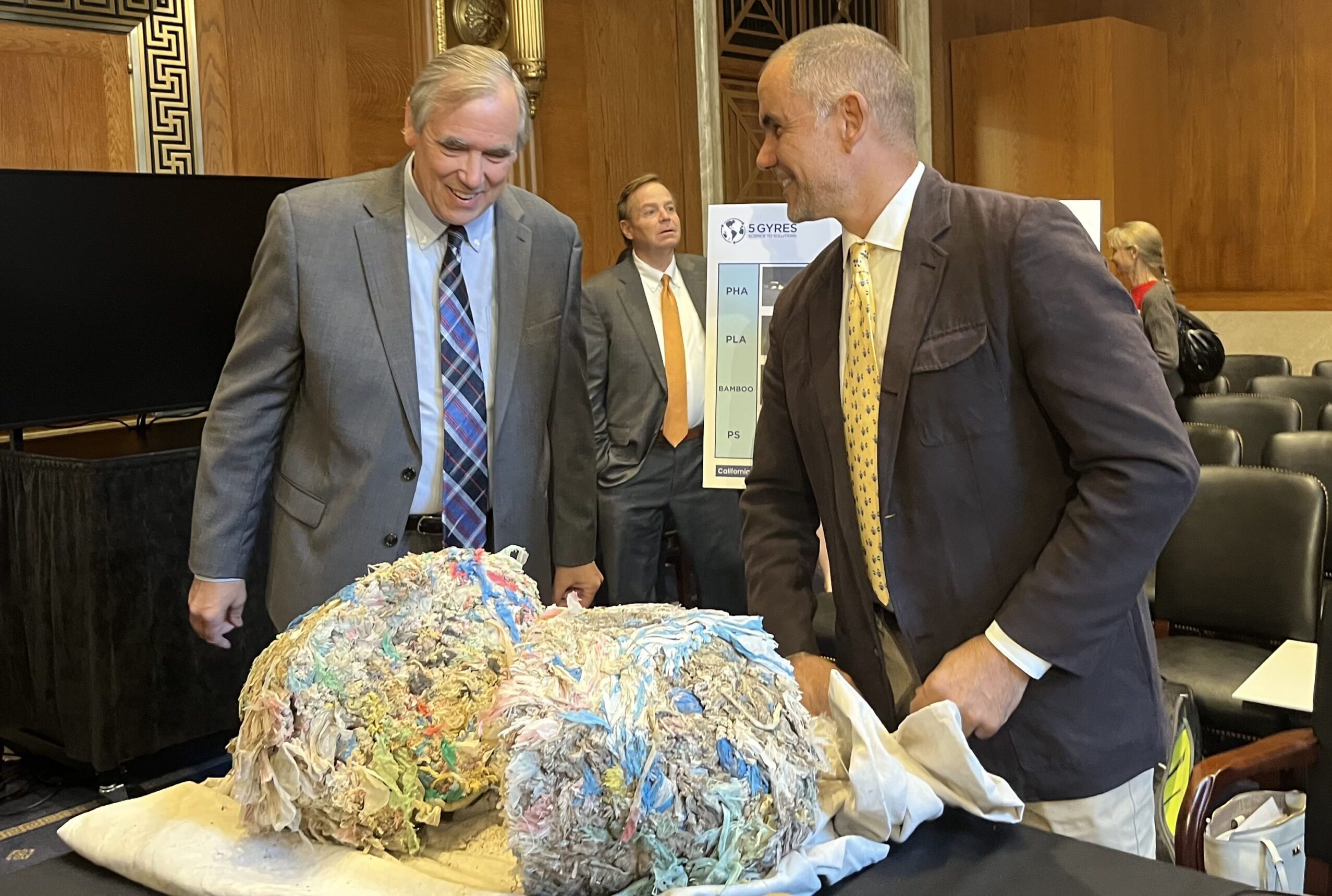 Sen. Jeff Merkley (D-Ore.), left, and witness Marcus Eriksen, right, discuss the plastic mass Eriksen brought to the hearing which he found in one camel.