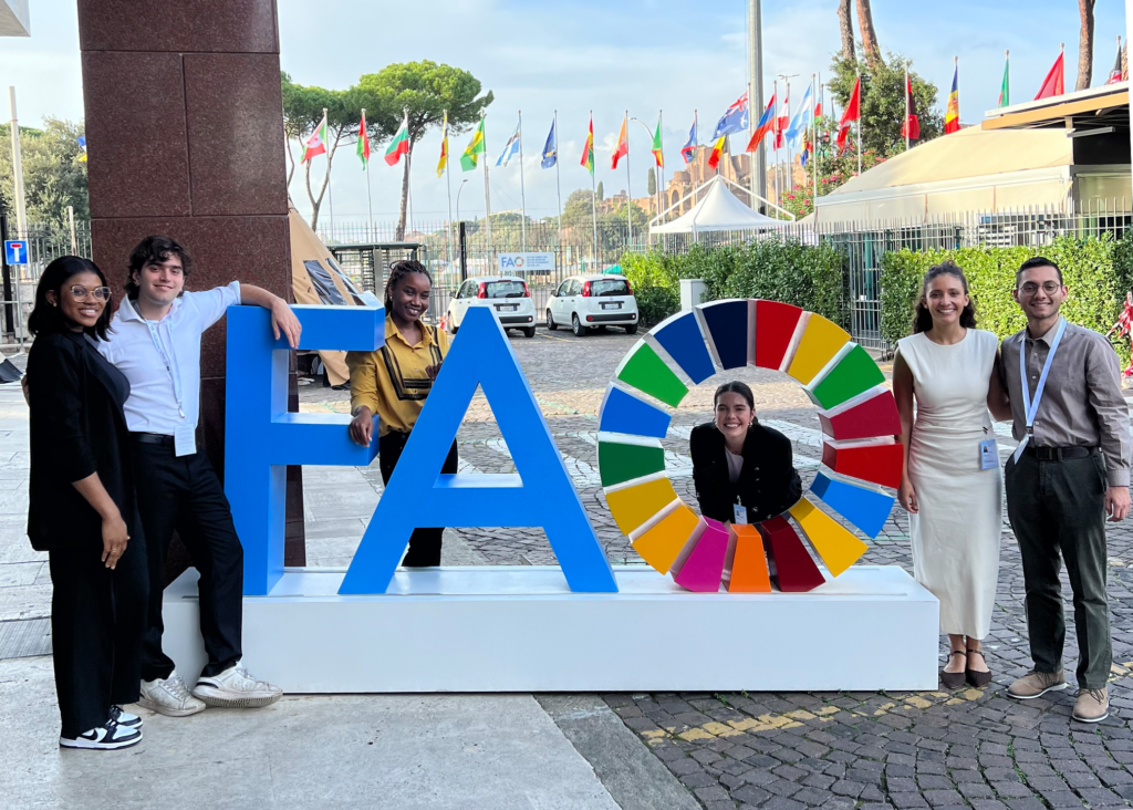 Students pose at a colorful FAO statue at the 2023 World Food Forum. 
