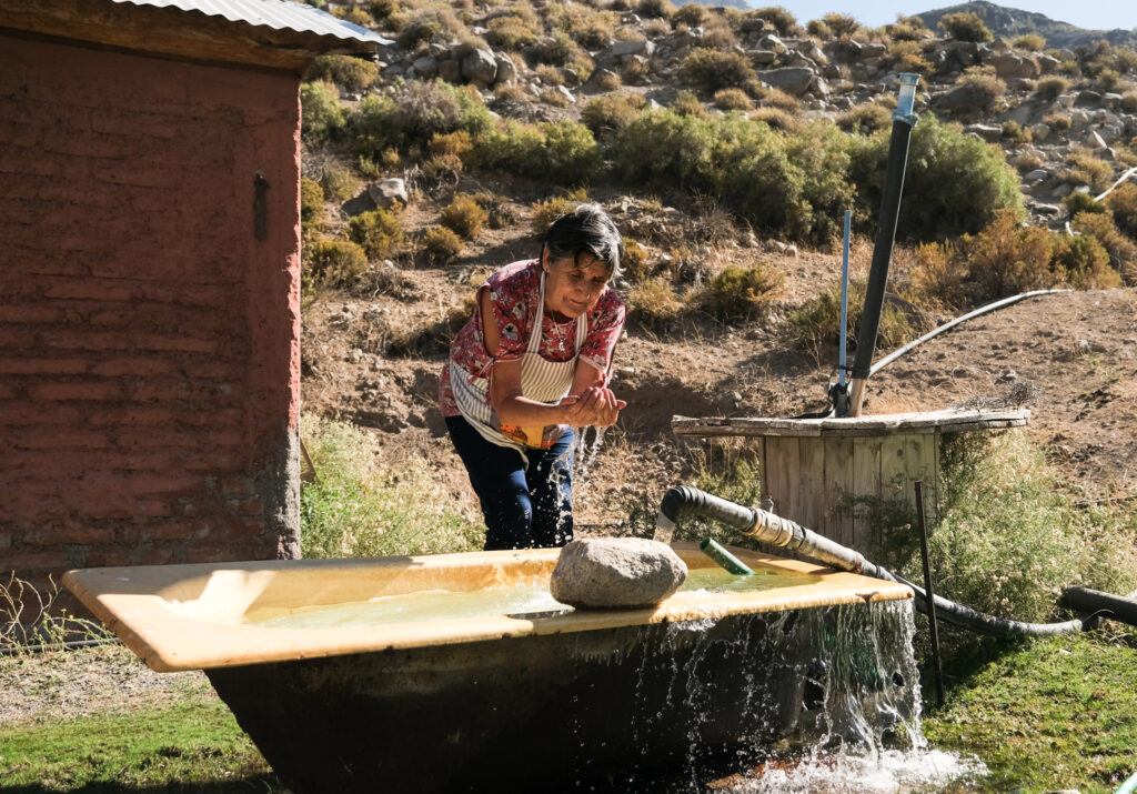 Victoria washes her hands with water from an old well outside of her childhood home in the mountains north of El Alfalfal, which remains abandoned after a natural disaster forced her family to relocate to within the El Alfalfal township.
