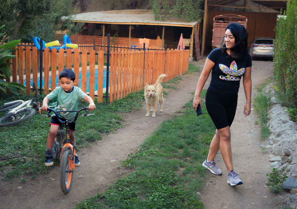 Jeni Gonzales and her son walk through their backyard in the township of El Alfalfal at dusk.
