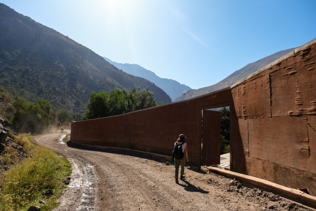 A journalist walks through a door in a remaining exterior wall of El Alfalfal. The wall was erected by AES Gener during the construction of Alto Maipo.
