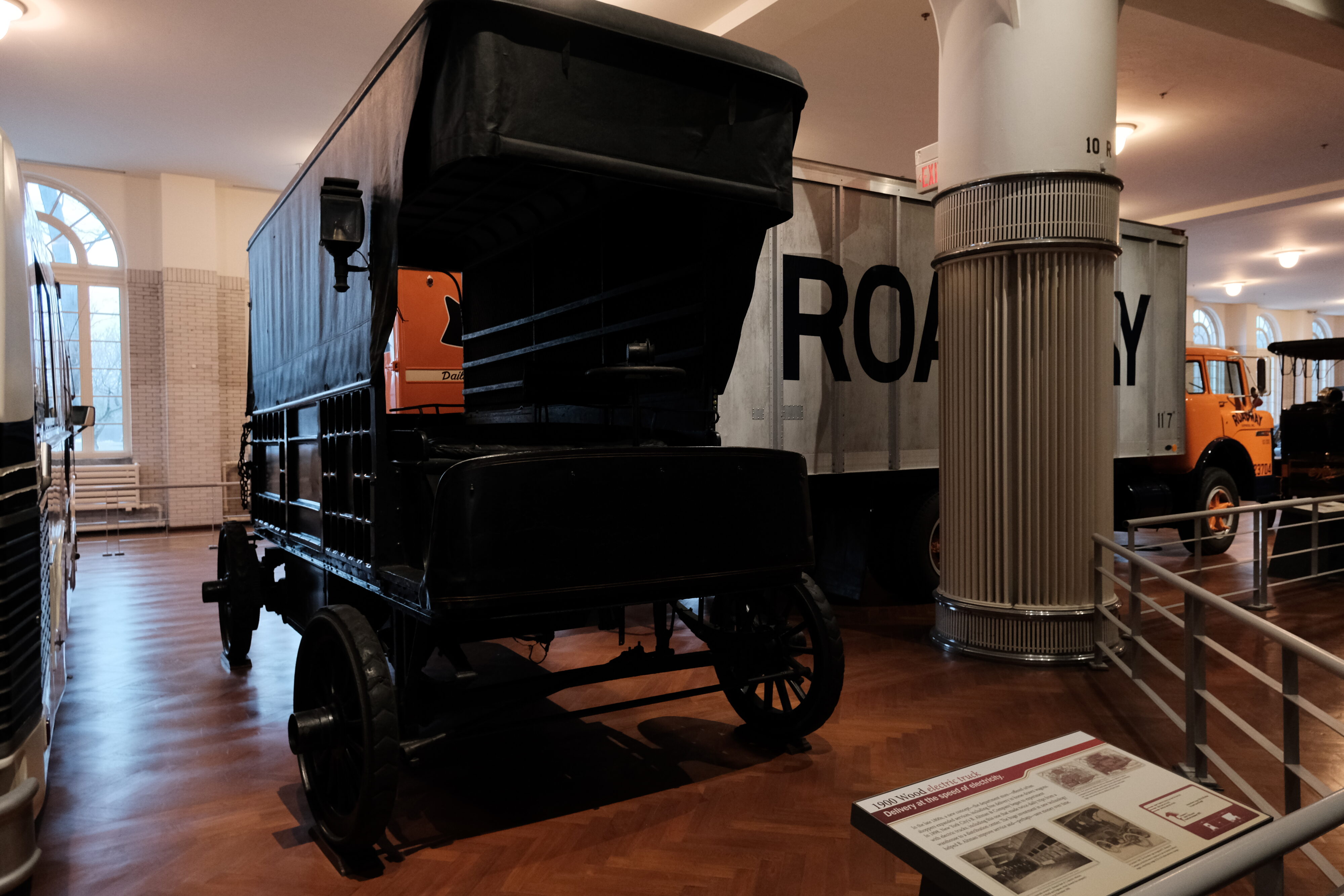A 1900 wooden electric truck sits in a museum floorspace. 