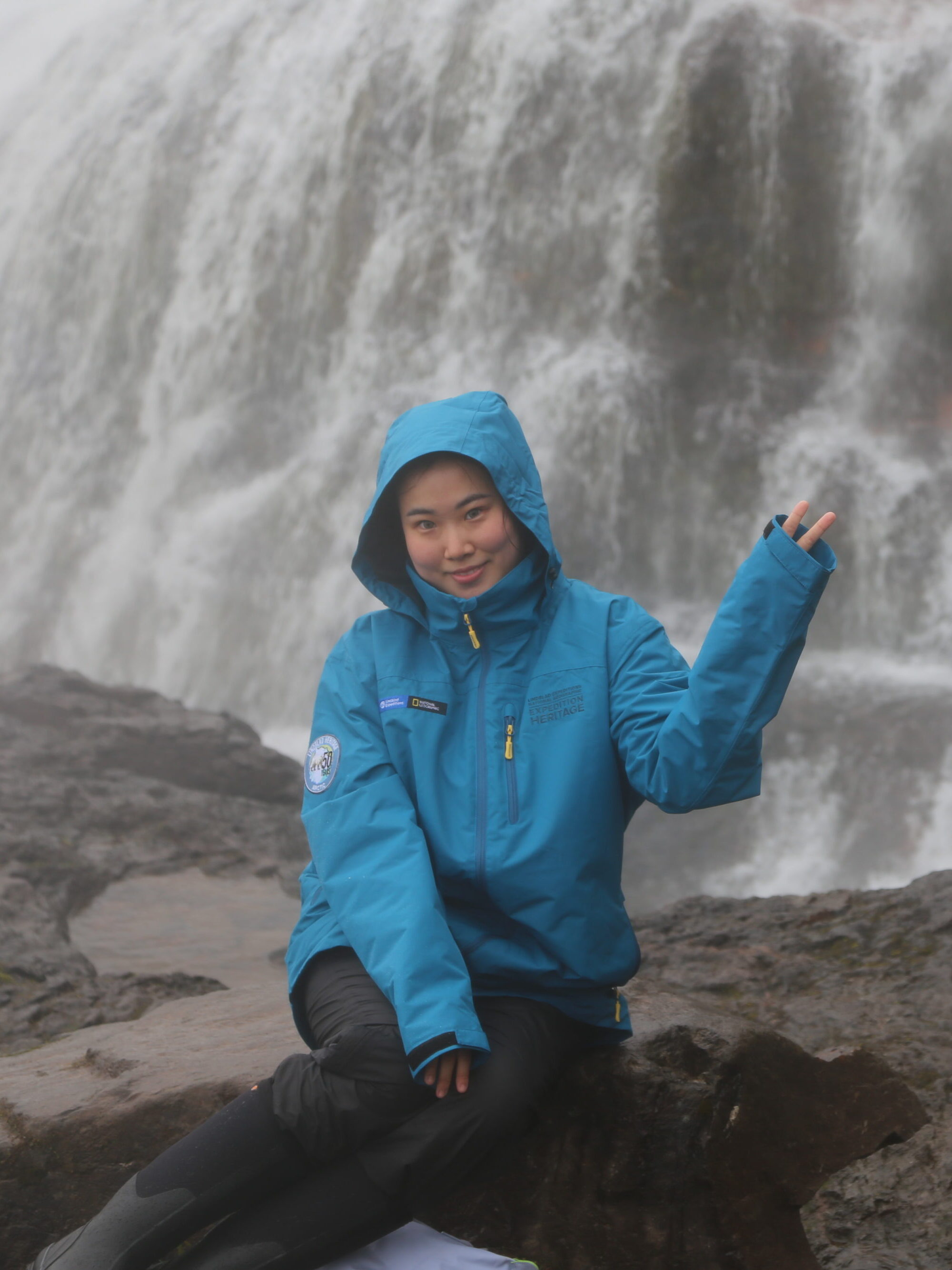 Delan Li sits in front of the waterfall