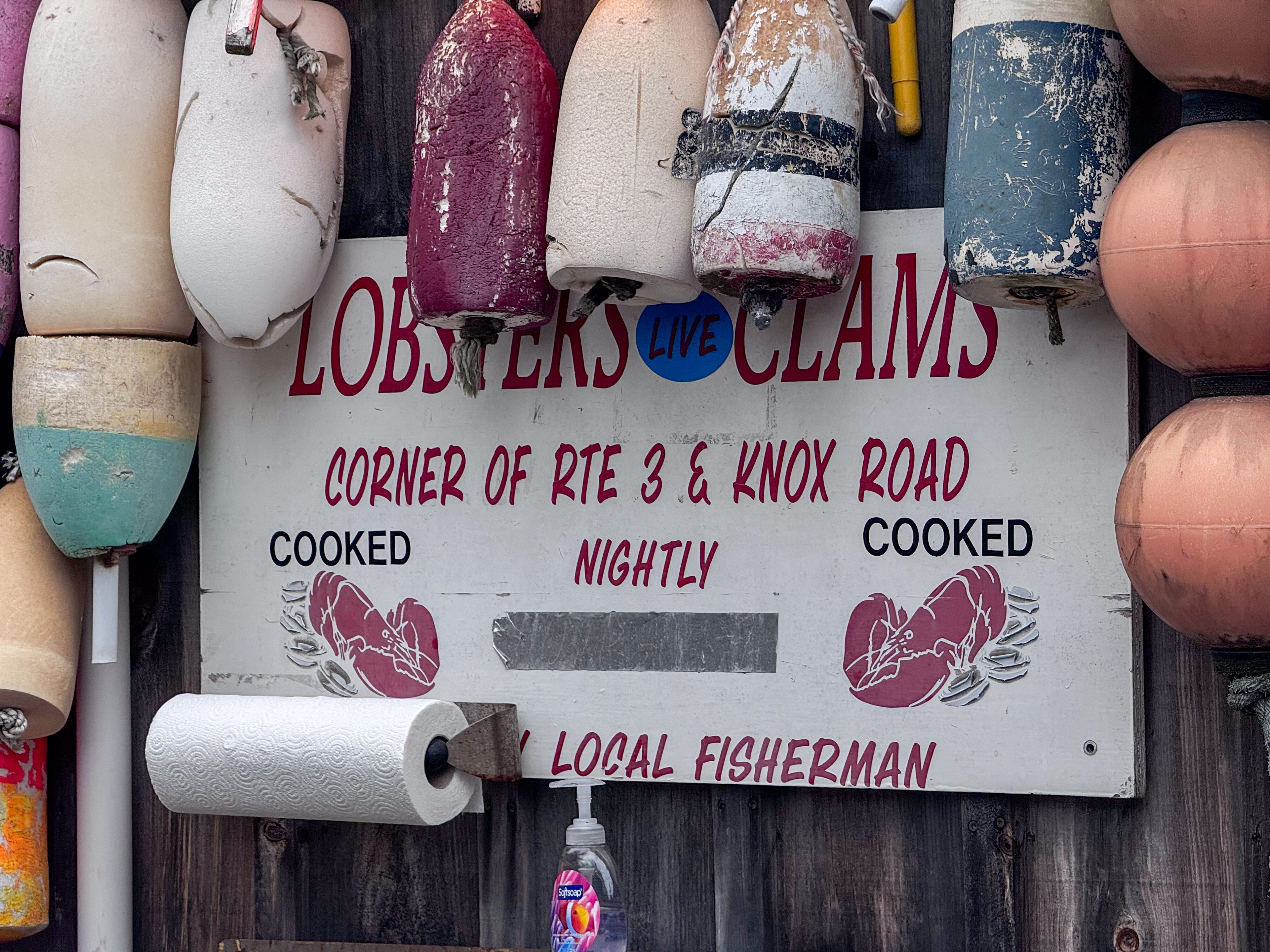 A sign on the exterior wall of the building reading, "Lobsters and Clams."