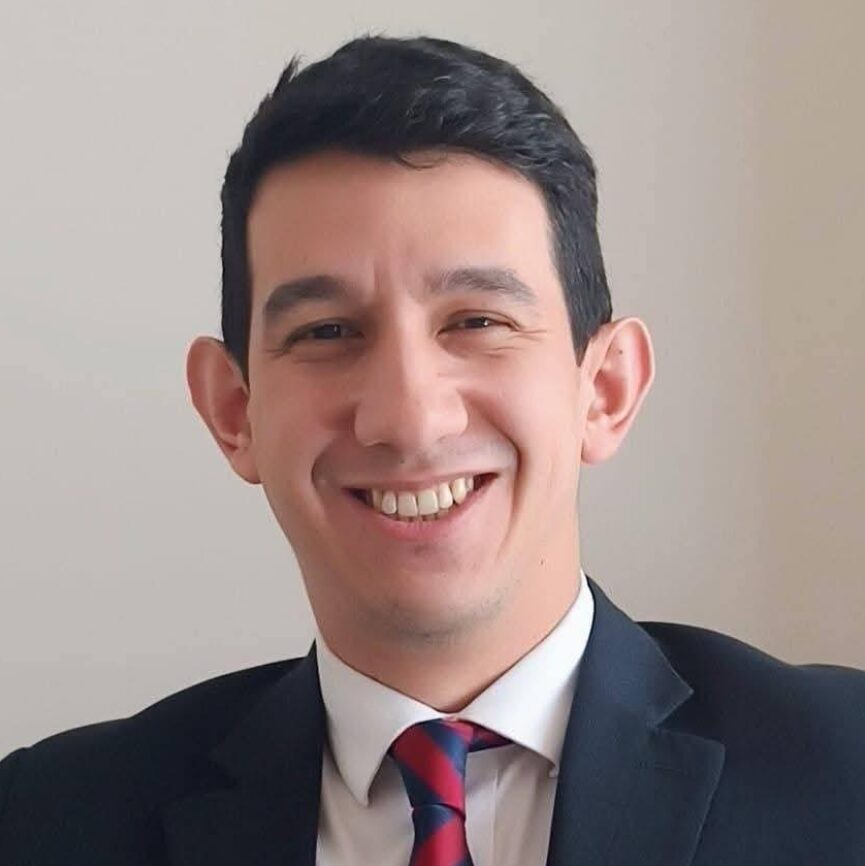 Headshot of a smiling man in a suit.