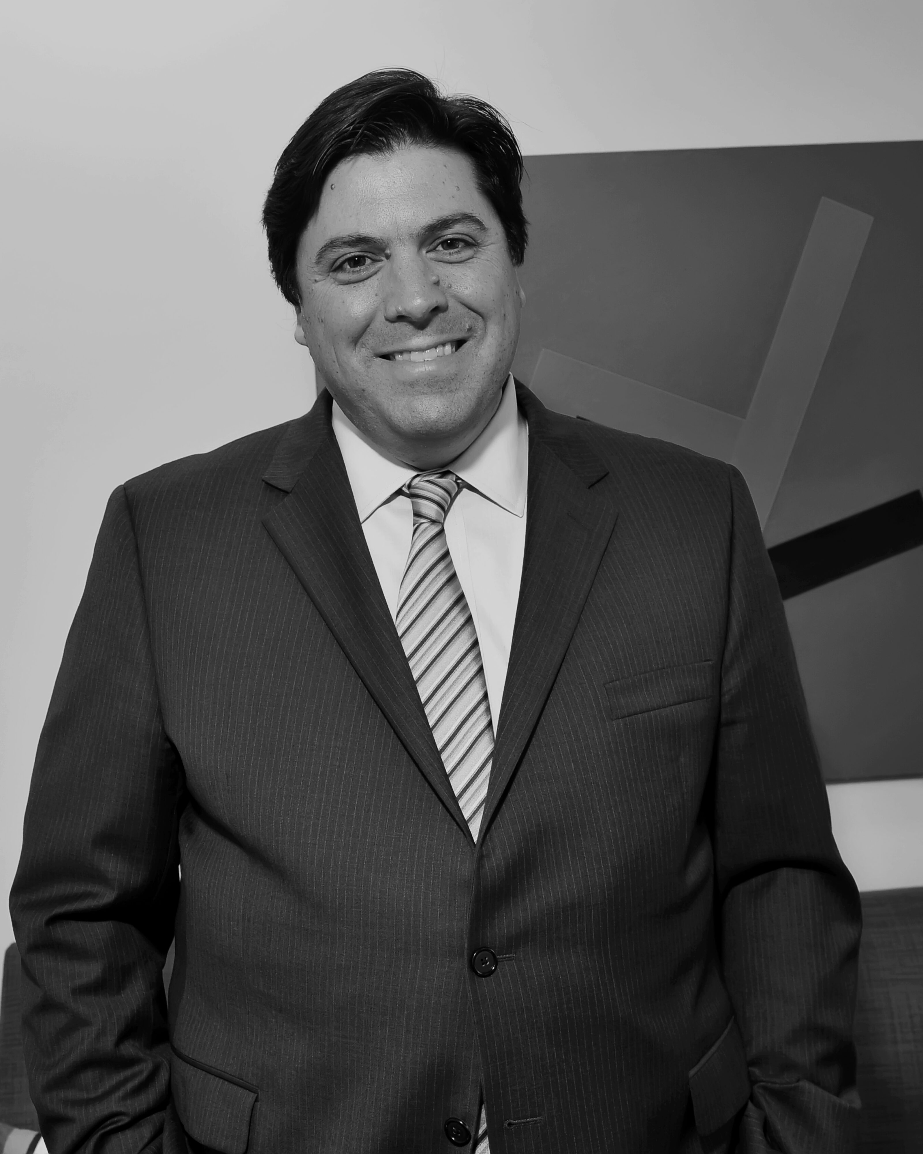 Black and white headshot of a smiling man in a suit.