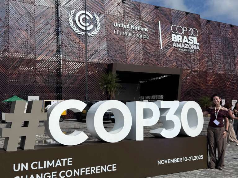 A student posing with a "COP30" sign.