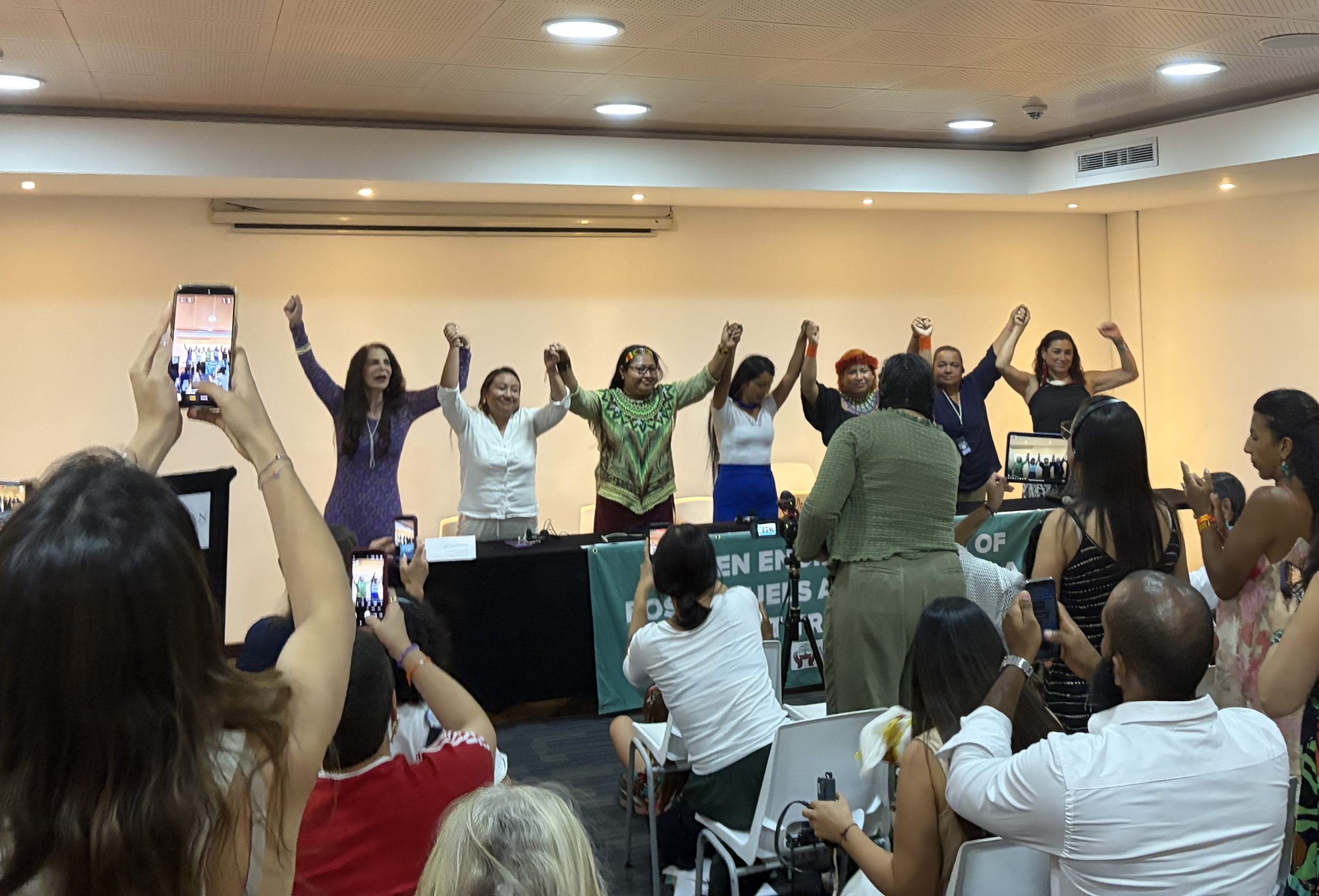 A group of panelists standing and joining hands.