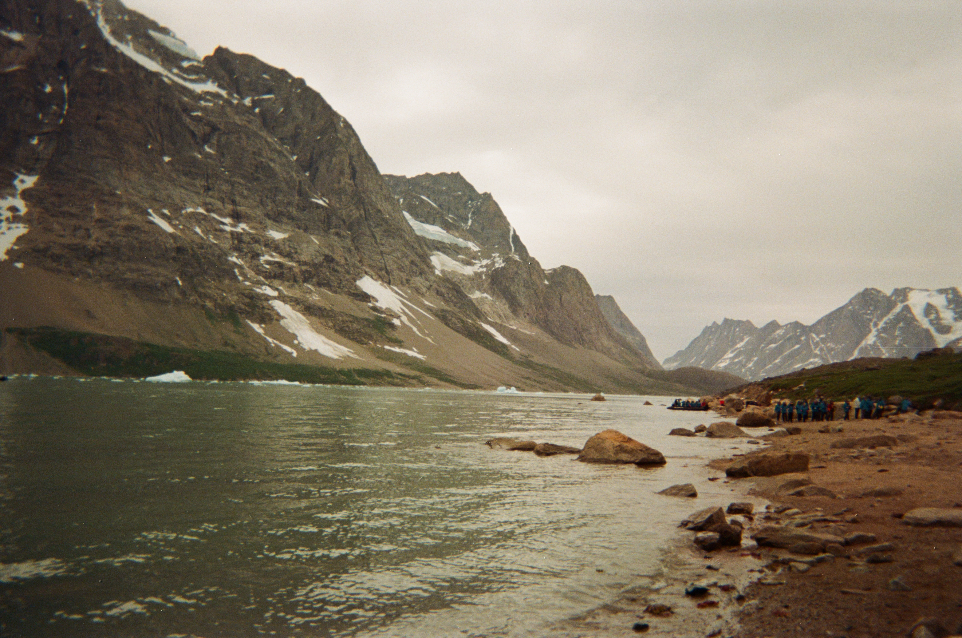 Visitors gather along the shoreline in southeastern Kalaallit Nunaat, surrounded by mountains, water, and lingering summer ice. Photo by Tommey Jodie.