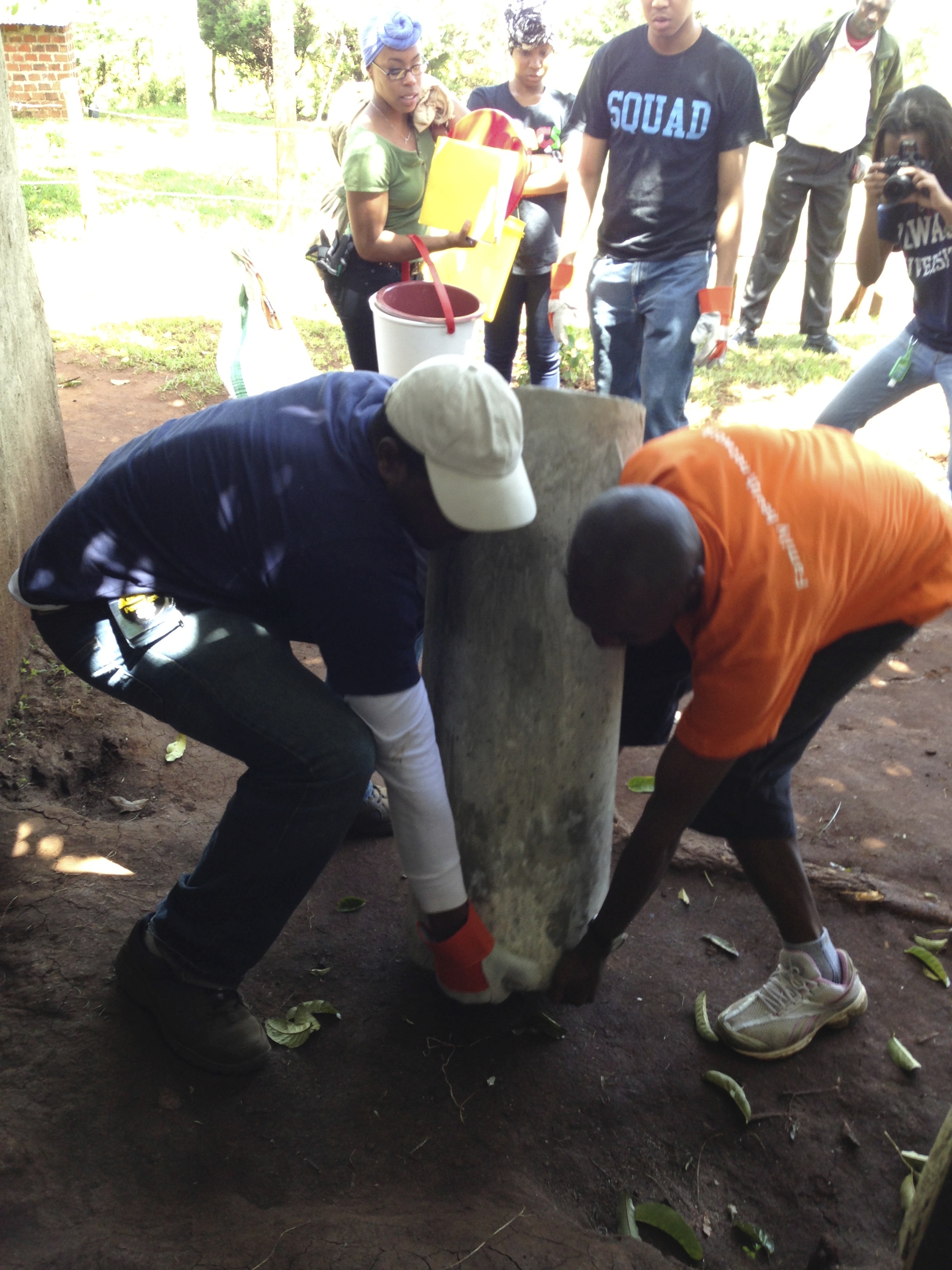Two people installing equipment in the dirt together.